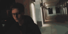 a man is walking down a dark hallway at night .