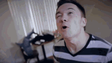 a man in a striped shirt is making a funny face in a room .