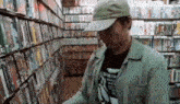 a man wearing a hat is standing in a book store looking at books .