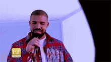 a man in a plaid shirt is singing into a microphone while wearing an et canada sticker on his shirt