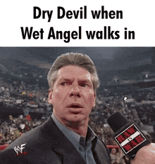 a man in a suit is talking into a microphone with the words dry devil when wet angel walks in below him