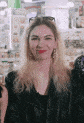 a woman wearing a black leather jacket and earrings smiles for the camera