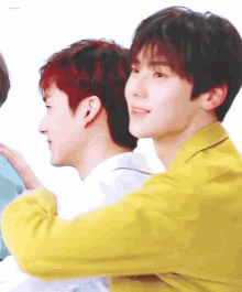 a man in a yellow jacket is hugging another man with red hair