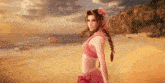 a woman in a pink bikini stands on a beach near the ocean