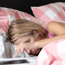 a woman is laying in bed with a cell phone on the bed