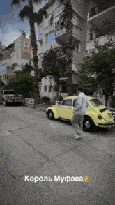 a yellow car is parked in front of a building and a man is walking by it