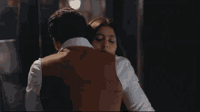 a woman with a ring on her finger is hugging a man in a suit