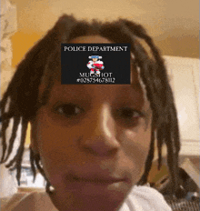 a person with dreadlocks has a mugshot from the police department on their forehead