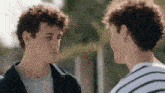 two men with curly hair are looking at each other .