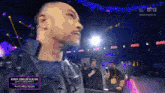 a man in a leather jacket is standing in a dark room with a sign that says kerry king of slayer