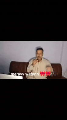 a man sitting on a couch with the words meravy watann on the bottom right