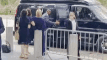 a group of people are getting out of a van behind a barrier .