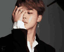 a close up of a person covering their face with their hand with a ring on their finger