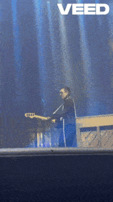 a man playing a guitar on a stage with the word veed on the bottom