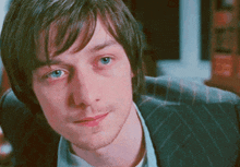 a close up of a man 's face with blue eyes wearing a suit