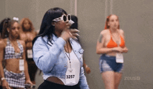 a woman wearing sunglasses and a name tag that says 3257 is standing in a room with other women .