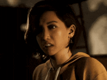 a woman with short hair is wearing a yellow sweatshirt