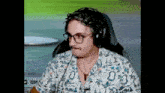 a man wearing headphones and a hawaiian shirt is sitting in front of a computer screen .