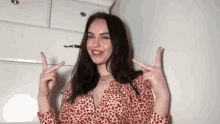 a woman in a red and white floral dress is making a peace sign with her fingers