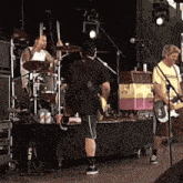 a man in a yellow shirt is playing a guitar while another man plays drums