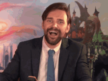 a man in a suit and tie is laughing in front of a painting