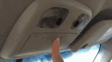 a person is pressing a button on the roof of a car .