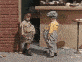 two children standing next to each other in front of a brick wall