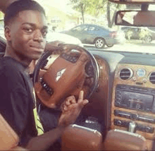 a young man is sitting at the steering wheel of a car .