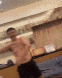 a man without a shirt is standing in front of a mirror in a kitchen