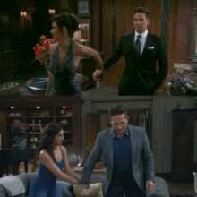 a man in a suit and tie stands next to a woman in a blue dress in a living room