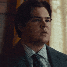 a man in a suit and tie looks to his left