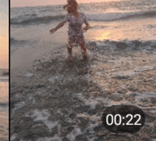 a girl is splashing in the ocean with a clock showing the time of 20:22