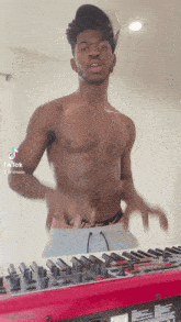 a shirtless man is standing in front of a keyboard .