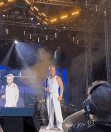 a man stands on a stage holding a microphone while a woman stands behind him