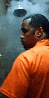 a man in an orange shirt stands in front of a shower