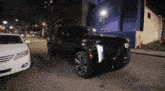 a black cadillac is parked in front of a white car