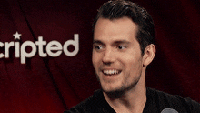 a man is laughing in front of a red curtain with the word scripted behind him
