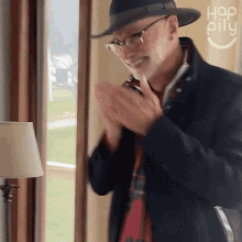 a man wearing a hat and glasses is clapping his hands in front of a sign that says hop pill