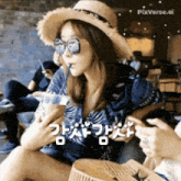 a woman wearing a hat and sunglasses is sitting at a table