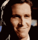 a close up of a man 's face smiling in a suit and tie .