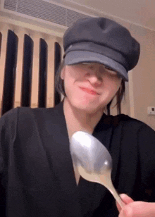 a woman wearing a hat is holding a spoon in front of her face .