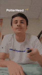 a young man is holding a wand with the word potterhead above his head