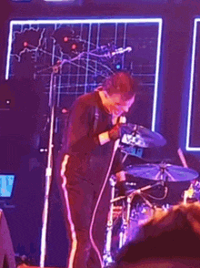 a man is singing into a microphone while playing drums