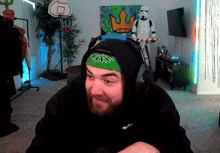 a man wearing headphones and a bandana is sitting in front of a storm trooper and a basketball hoop .