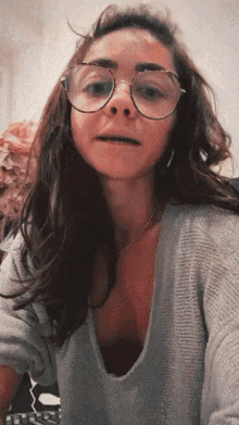a woman wearing glasses and a sweater is making a face