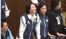 a group of women are standing next to each other in front of a table in a room .