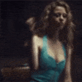 a woman in a blue dress is sitting down in a dark room .