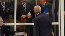 a man in a suit and tie is standing in front of a glass door talking to another man in a suit and tie