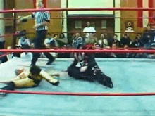 a wrestling match is going on in a ring with a referee in the background