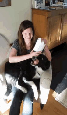 a woman sitting in a chair with a dog on her lap